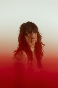 The photograph shows Sofia Boito. Her face is covered by her hair, and her portrait gently fades into a red haze that surrounds her.