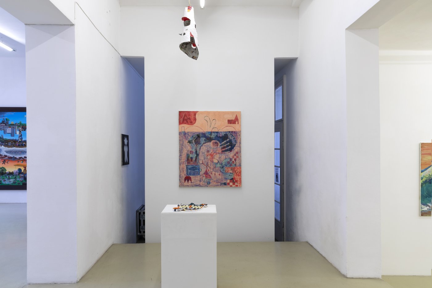 exhibition view with paintings and an installation