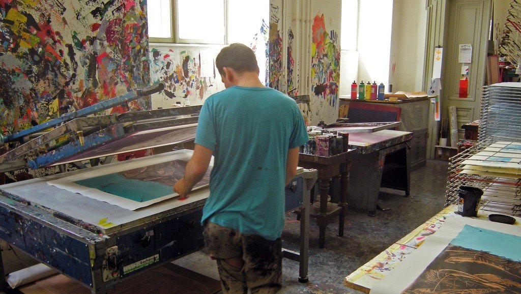 A student stands in front of the screen printing machine.