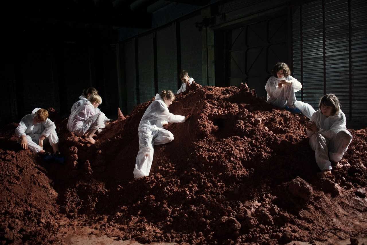Women in white overalls on a mountain of earth
