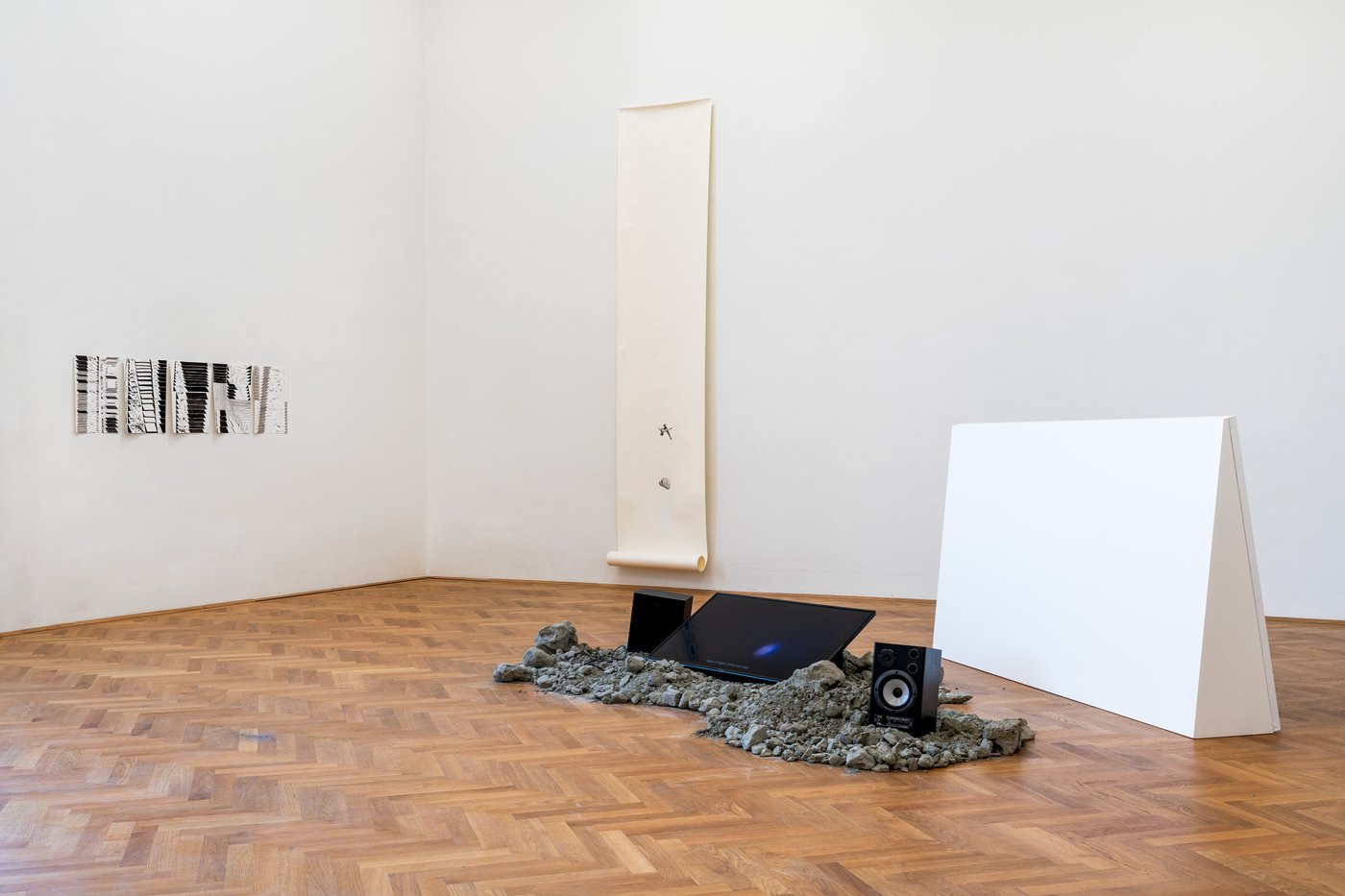 Art installation with a TV on the floor and art works on the wall