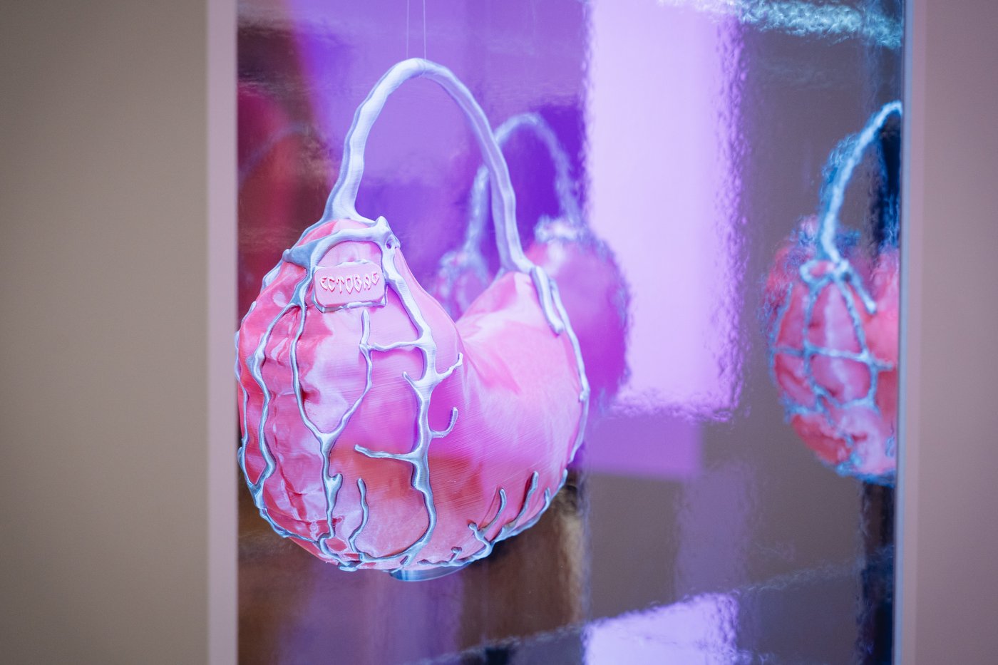 pink objekt that reminds of a bag in a mirrored cube with blue light