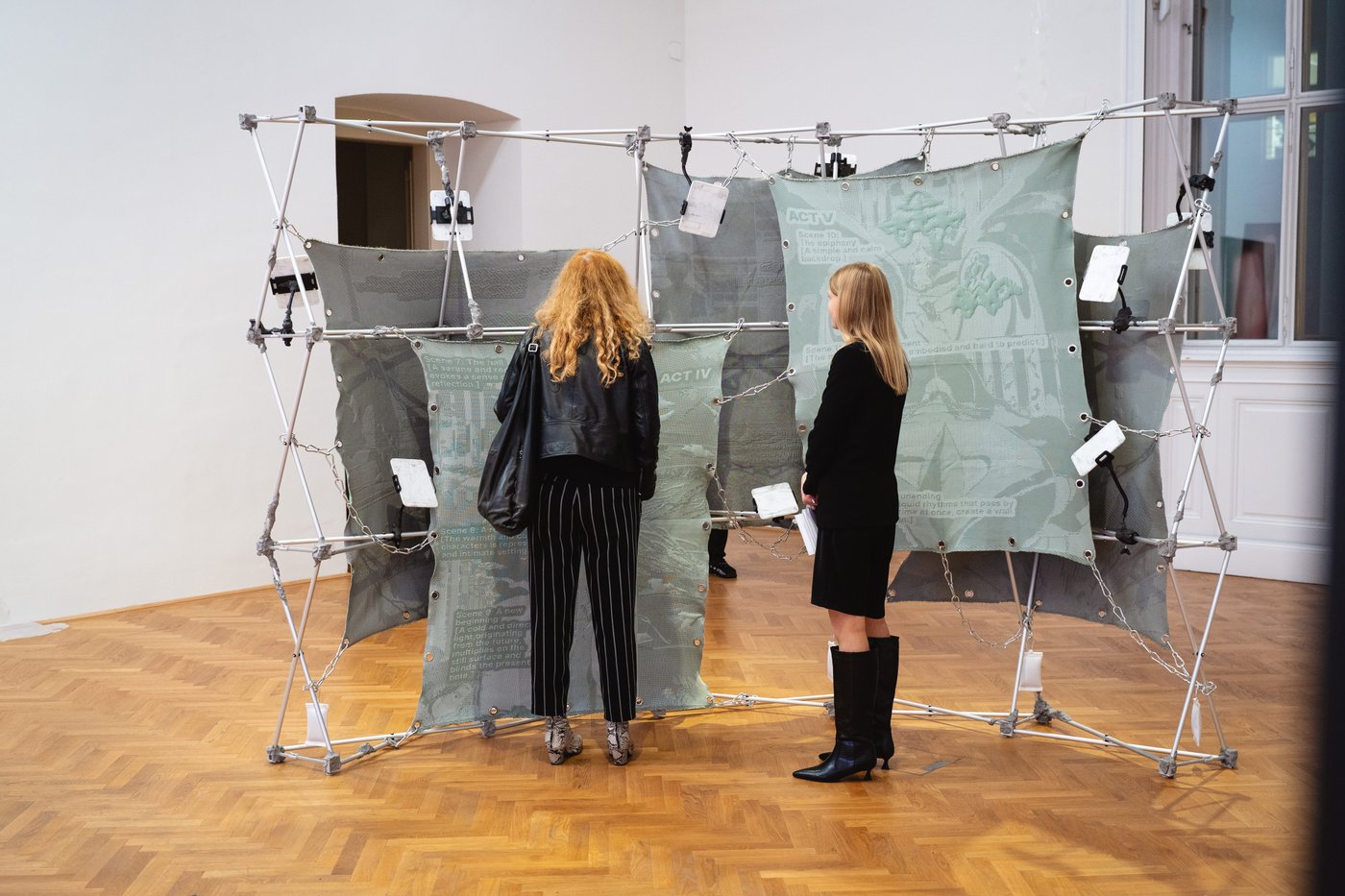 two people in the exhibition standing in front of a large green artwork