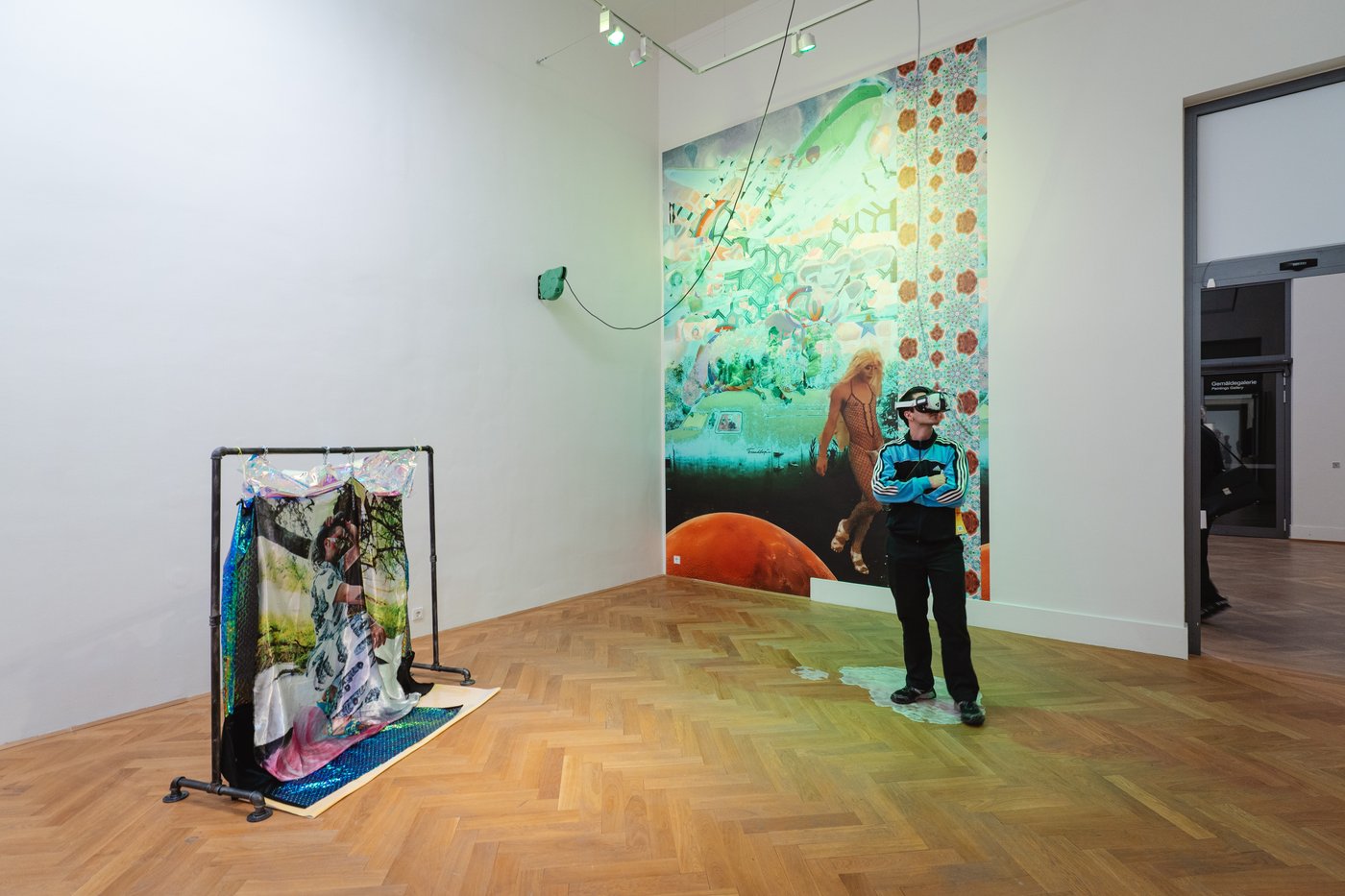 colorful material hanging from the wall and on a construction with a person in the middle of the room who wears VR glasses