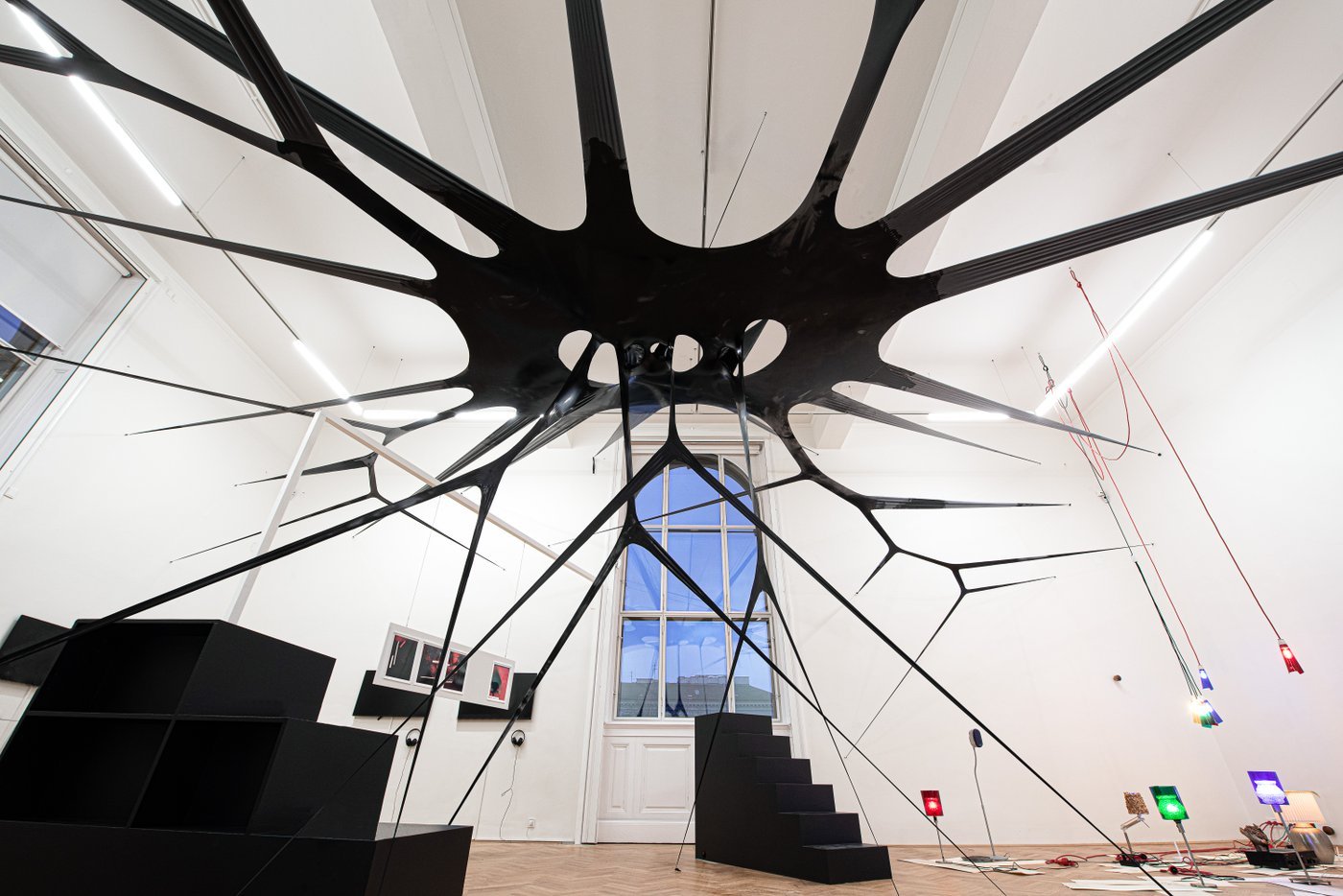 View of an exhibition room with a black spider-like structure in the center