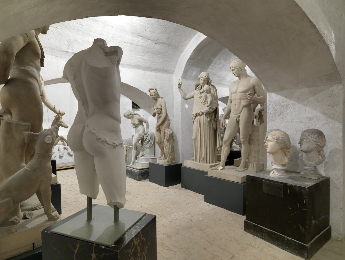 Photo of a room with vaults in which several Greek sculptures in different poses are standing close to each other