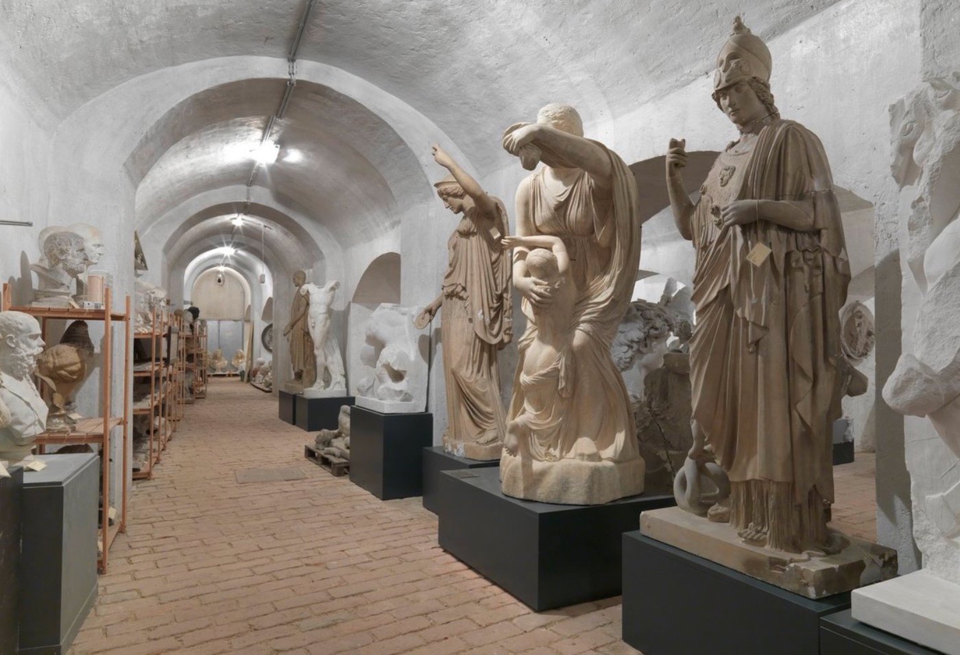 a few figures, heads and full body, in a white painted cellar