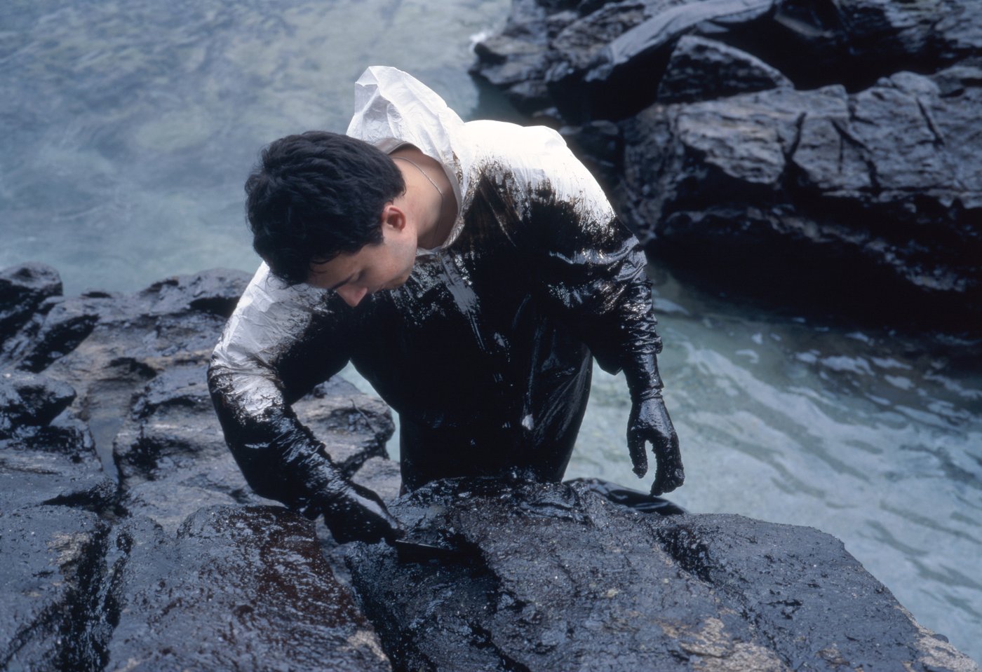 a photo of a man standing in the sea polluted with oil