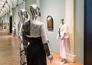 two metal puppets human size dressed in artworks in a long hallway.