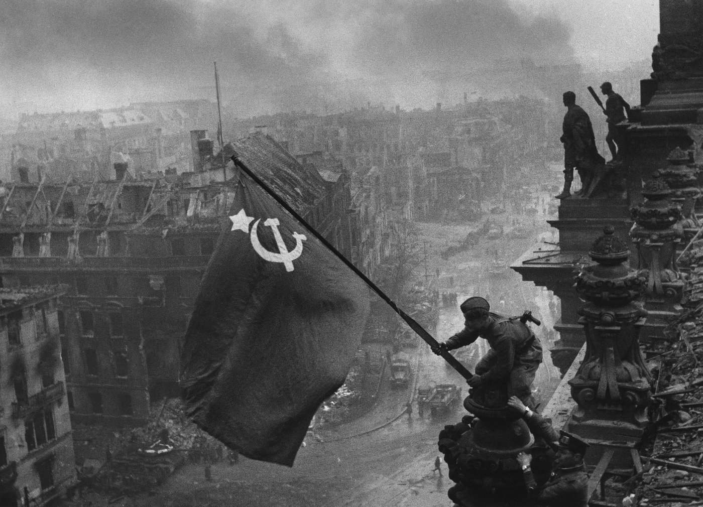 black and white picture of a flag and destroyed buildings in a city in the background