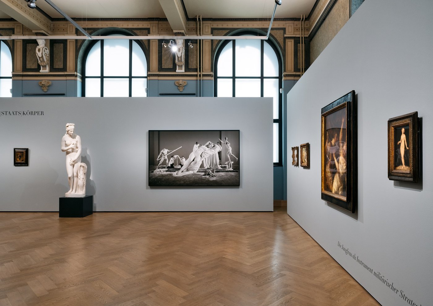 fotograph of a blue exhibition room with a sculpture and some works on the walls