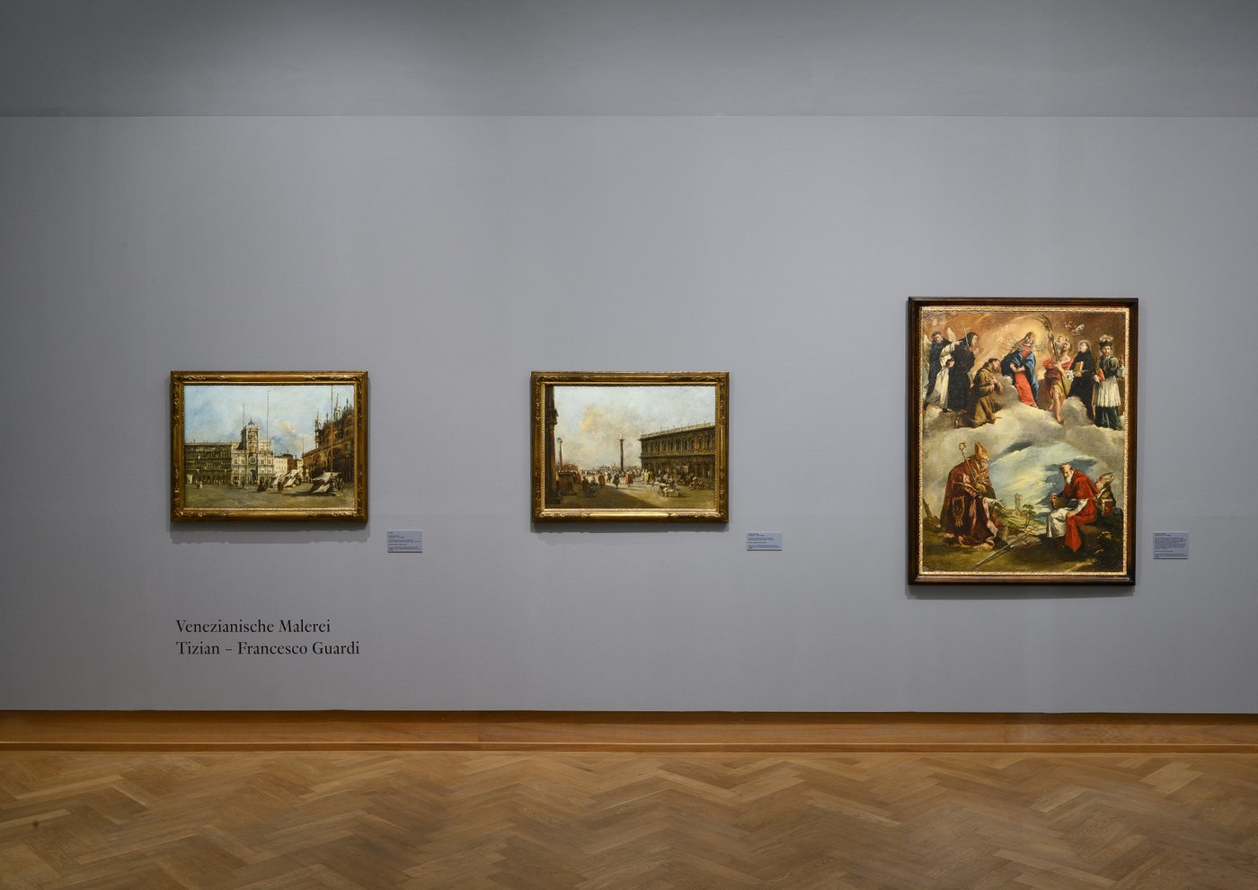a blue grey painted exhibition room in an old building with framed old paintings on the wall
