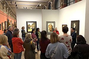 a group of people in an exhibition tour before a few painings