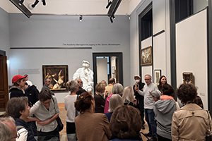 Visitors during a guided tour of an exhibition in a museum gallery.