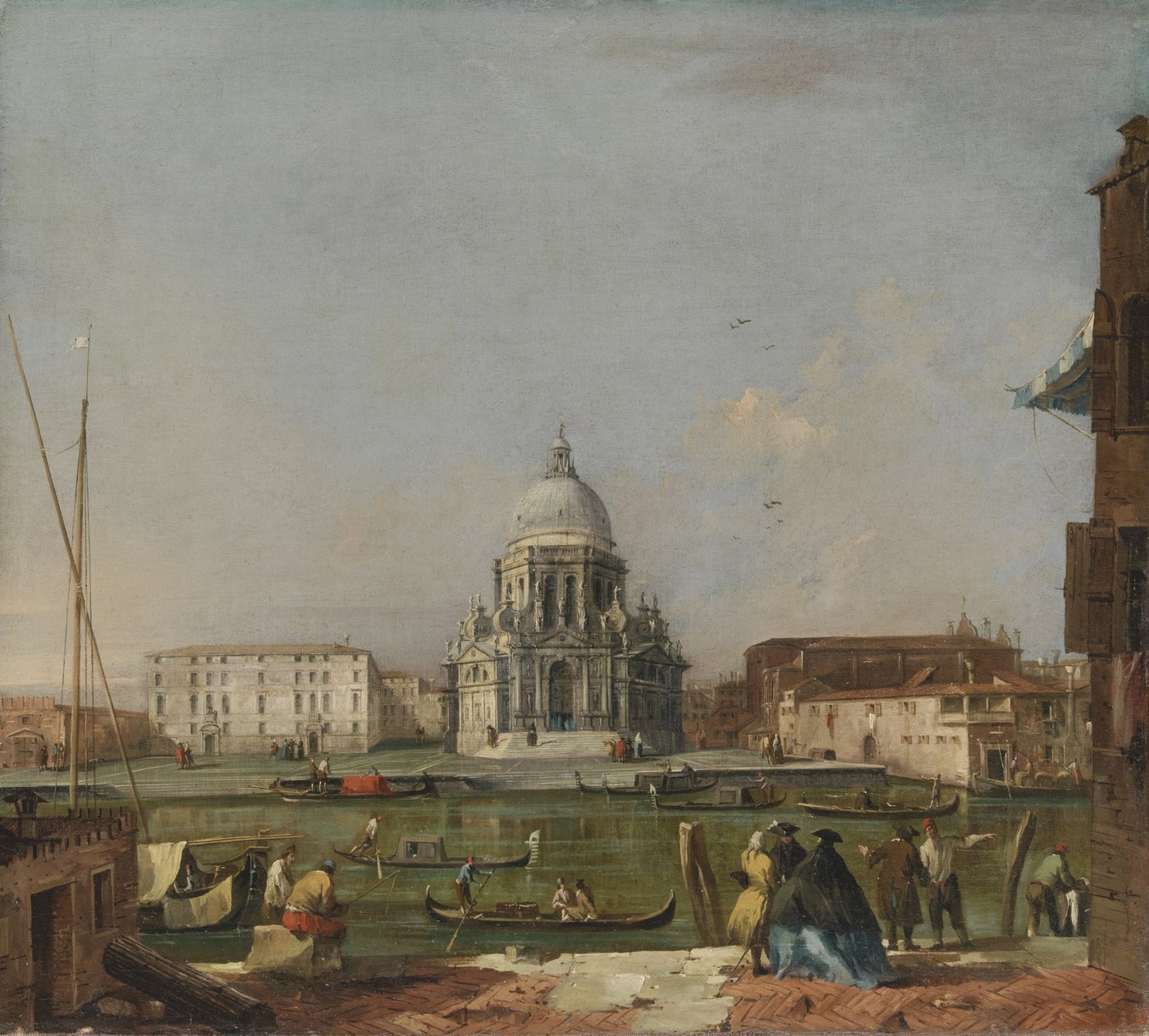 A historical painting of a Venetian city view on the canal. In the center of the picture a white church with a green dome surrounded by plain buildings. In the foreground are working people crossing the river on their boats and nobles in baroque clothes with hats standing together in a group.
