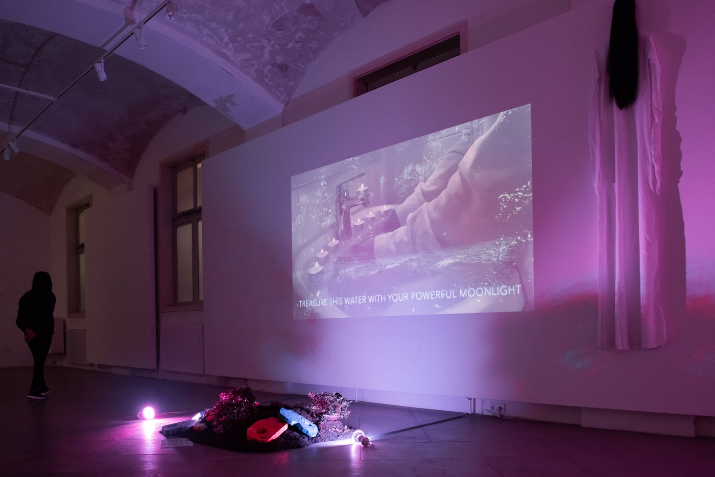 Exhibition view of a room with a video streaming, Still of the Video, the room is colored in pink