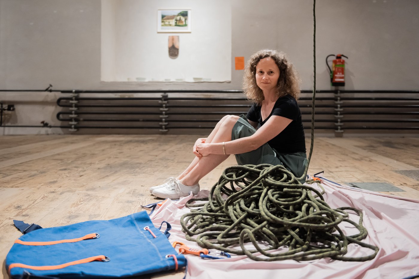 A woman sitting on the floor and in front of her is a pile of ropes
