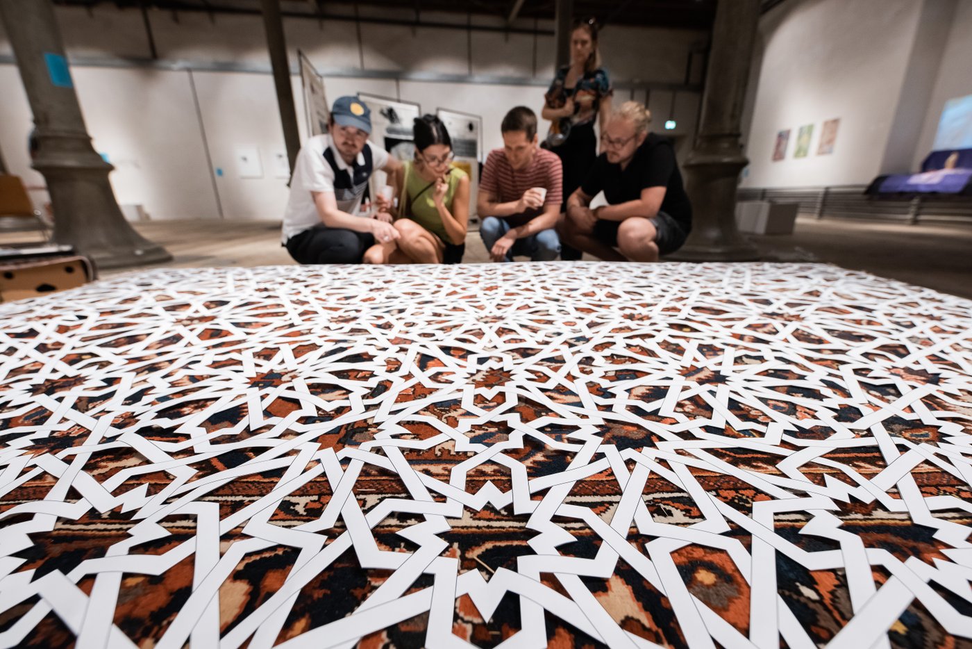 People looking on the artistic carpet with white cut-out on the floor
