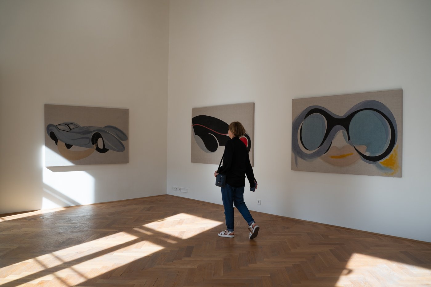 One person in front of three painting with cars