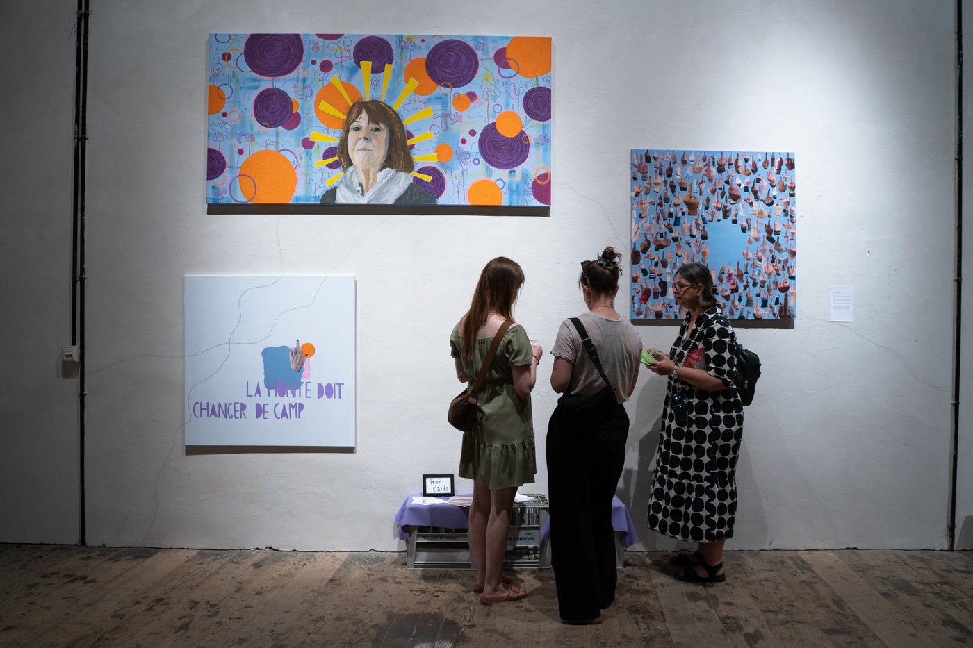 Three people in front of painting with one Gigele Pelicot