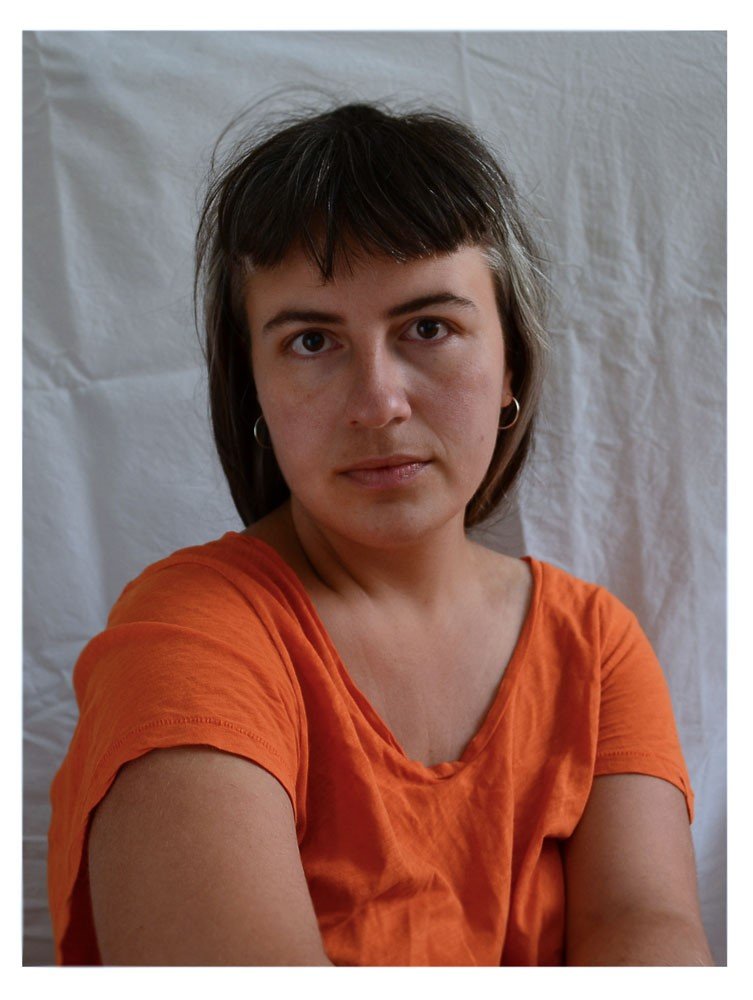 Picture of a women with dark hair and a Shirt that looks into the camera