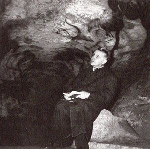 Georges Bataille sits in the Lascaux cave with a notepad and looks up at the ceiling.