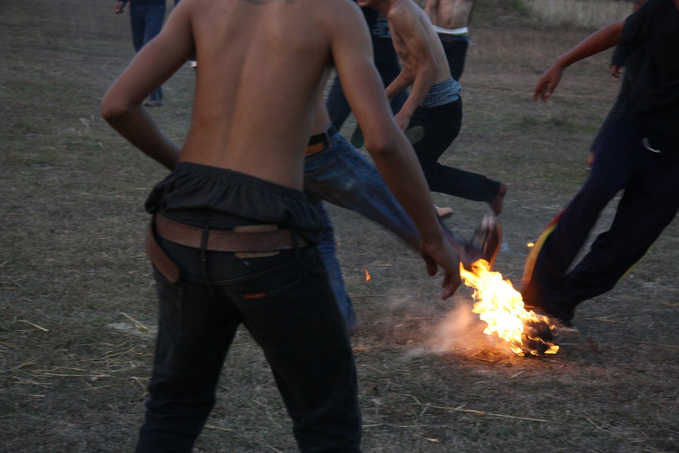 Legs, feet and partly naked upper bodies around a burning ball.