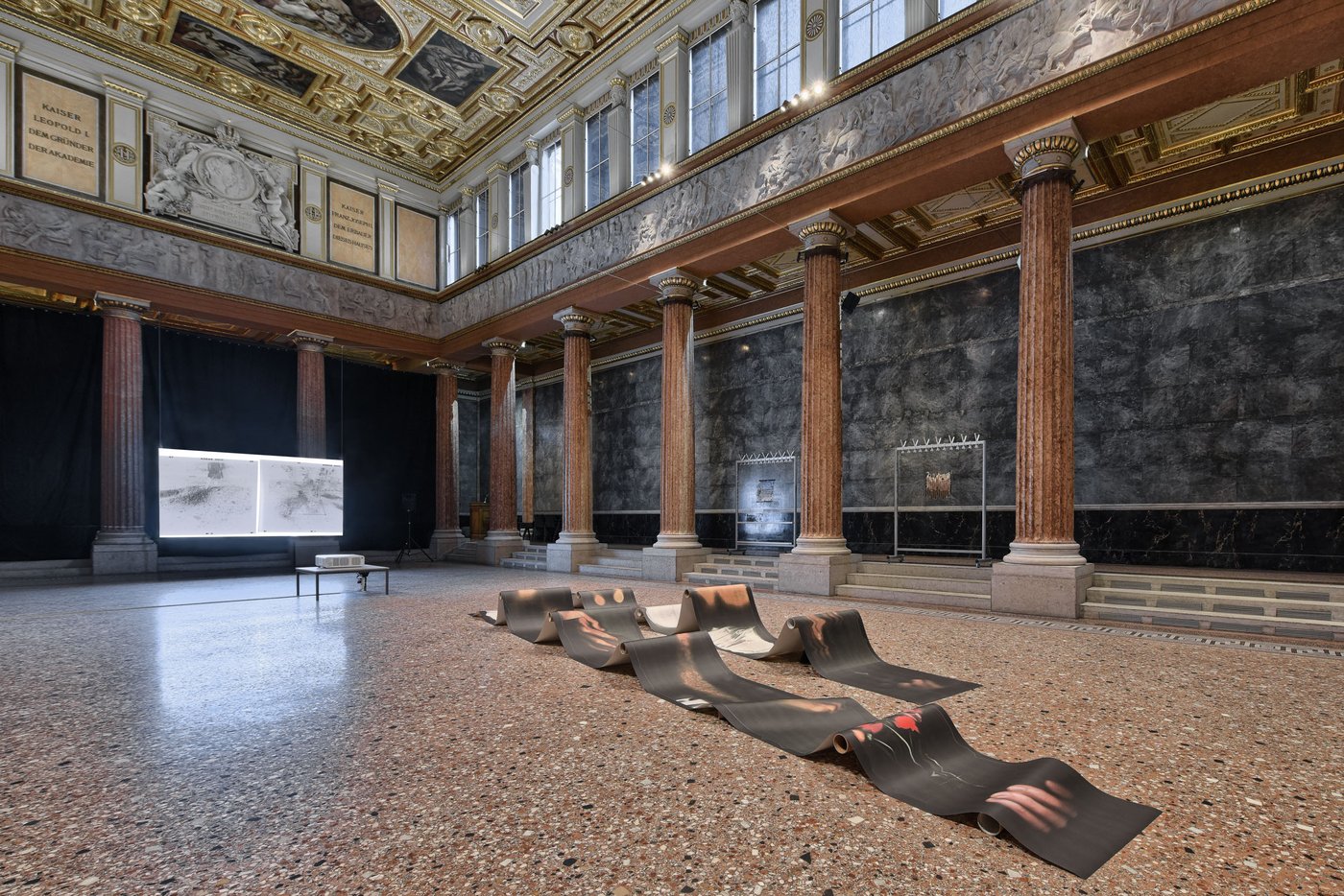 Aula of the academy with a wave-shaped paper installation and a screen in the background