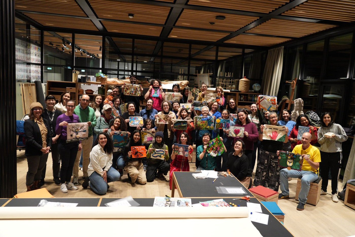 A group of people smiling into the camera and holding up their artworks