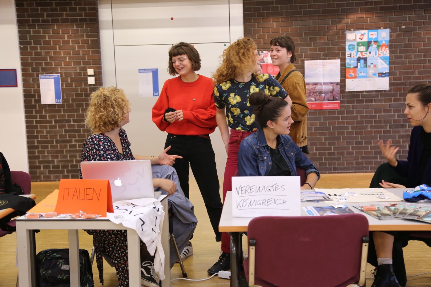You can see incoming exchange students from Italy and the United Kingdom in lively conversation with students interested in studying abroad. A poster on the back wall draws attention to the Erasmus plus mobility program.