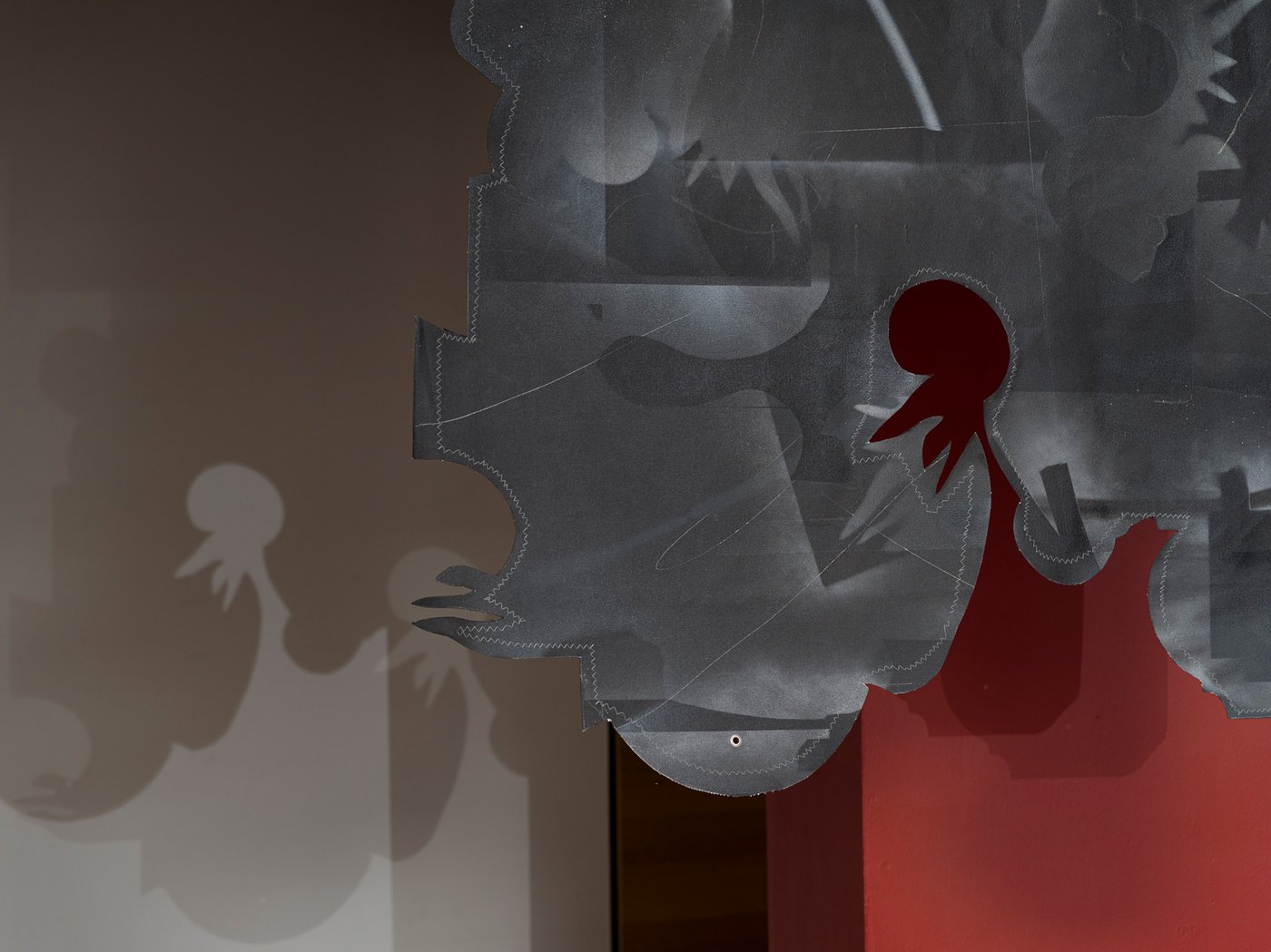 This landscape-oriented graphic work is rendered in dark shades of gray and brown, with a red area at the lower right edge of the image. It challenges our perception and allows for multiple interpretations depending on where we focus.