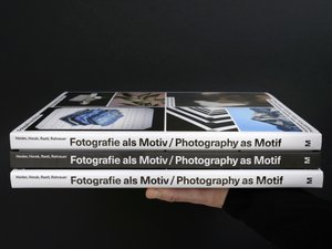 A stack of three copies of the book Photography as Motif showing the spine and a front cover.