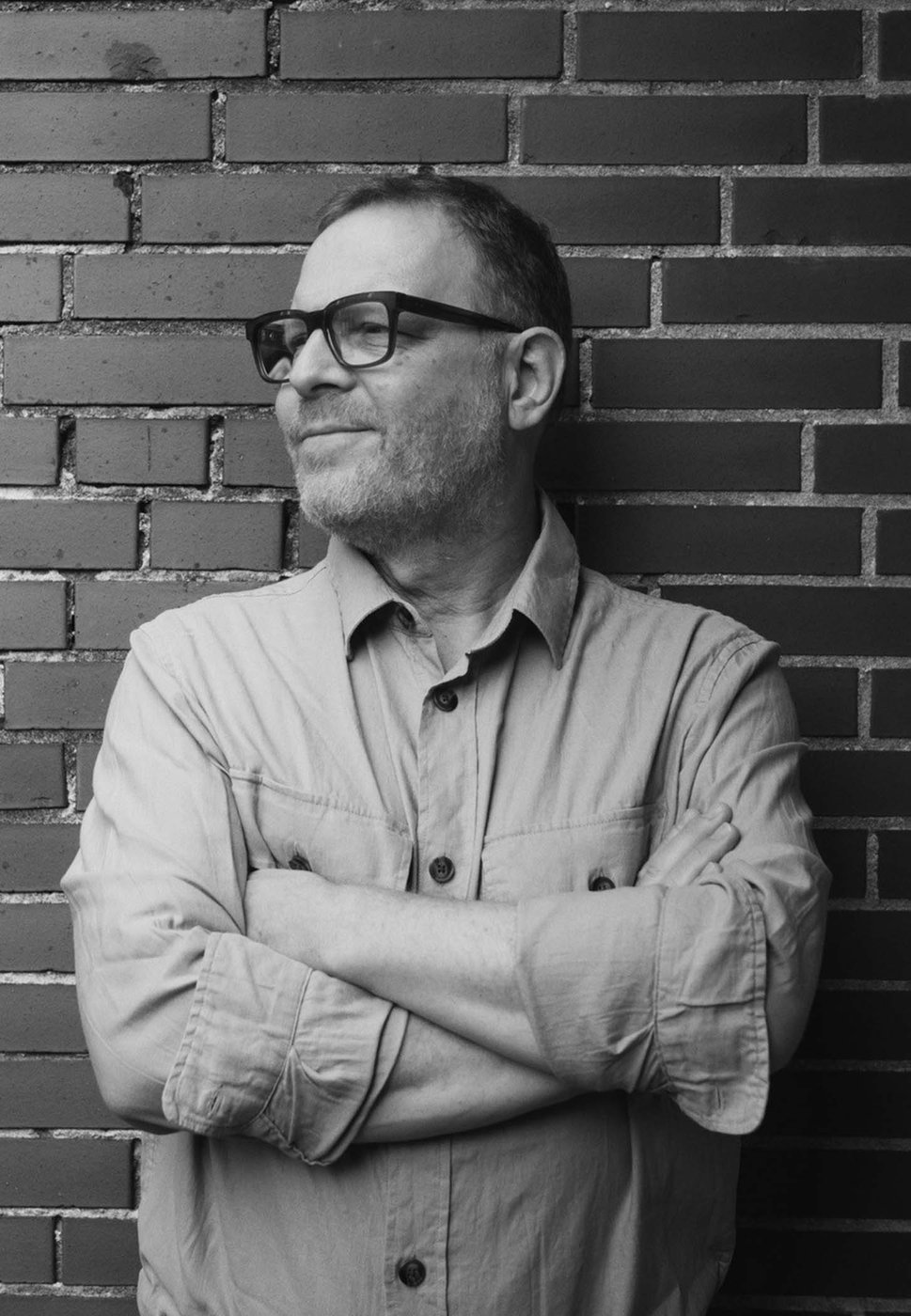 B/W portrait of the author standing in front of a brick wall (portrait format).