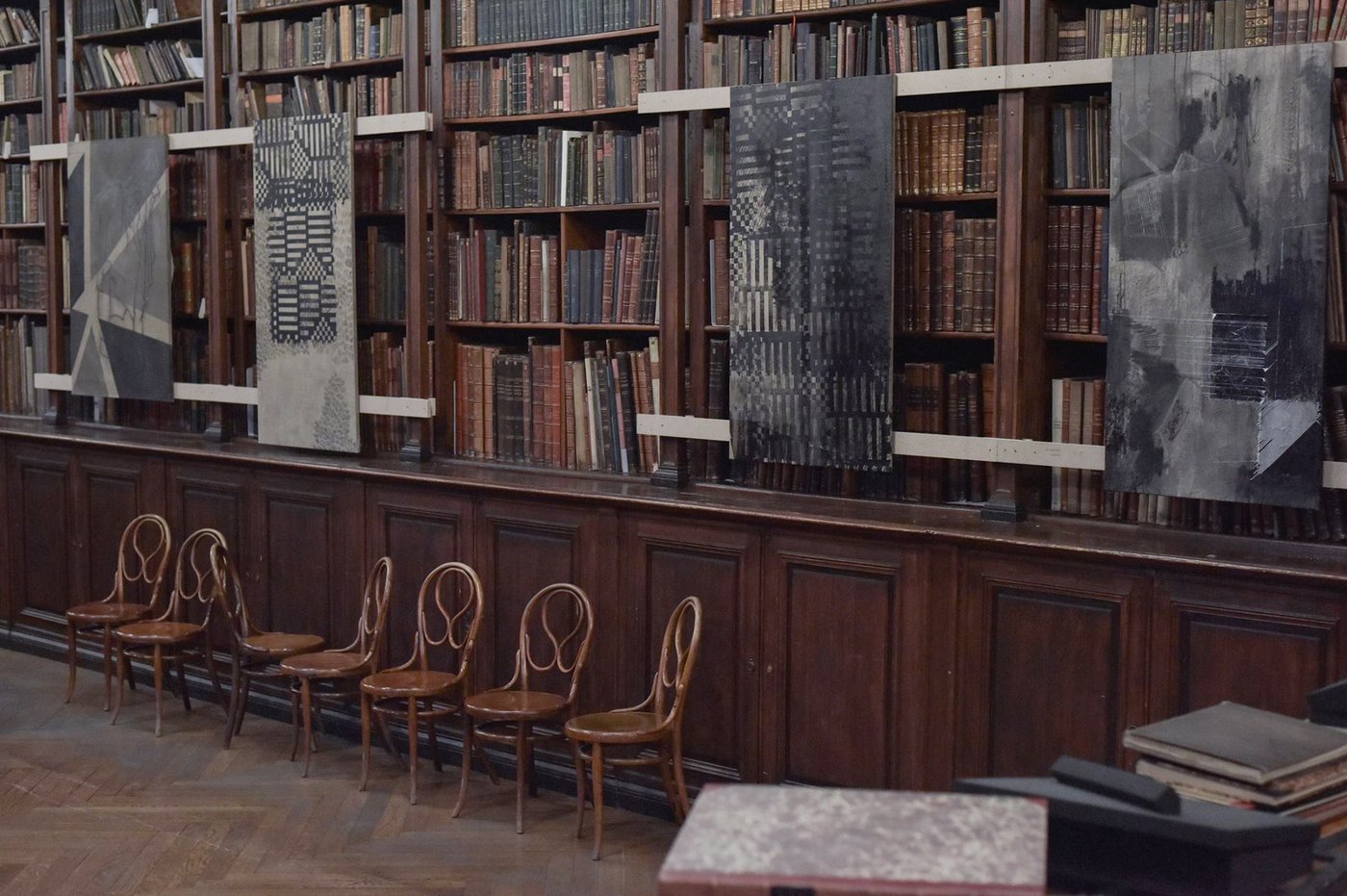 Four paintings by Christian Murzek hung along the library shelves.